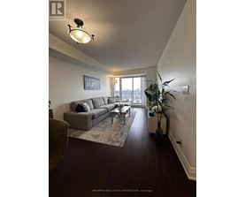 A living room with a grey couch and a large window.