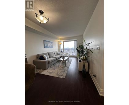 A living room with a grey couch and a large window.