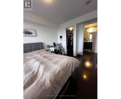 A bedroom with a large bed and a closet with clothes hanging.