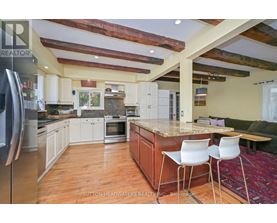 A kitchen with a refrigerator on the left and a table with two chairs in the middle.
