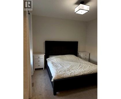 A bedroom with a bed, nightstand, and dresser.