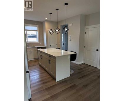A modern kitchen with a white island and wooden floors.