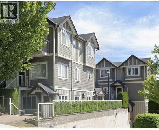 A real estate sign is in front of a row of houses.