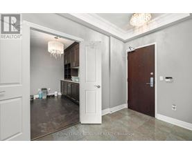 A room with a chandelier and a door leading to a kitchen.