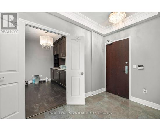 A room with a chandelier and a door leading to a kitchen.