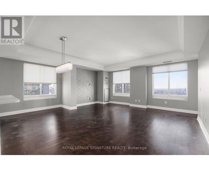 A spacious room with wooden flooring and a large window.