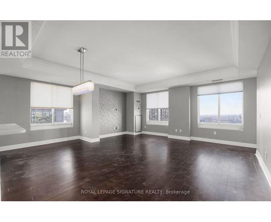 A spacious room with wooden flooring and a large window.