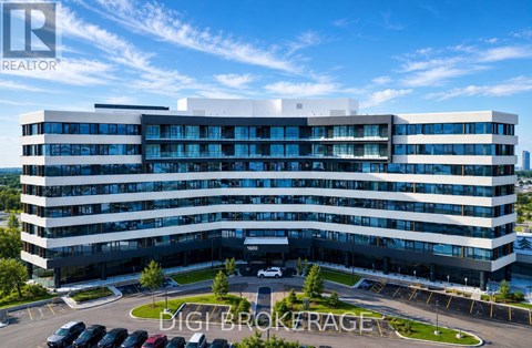 A modern multi-story building with a parking lot in front.