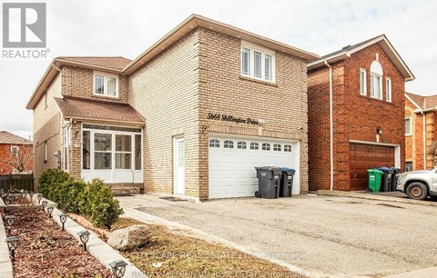 A brick house with a white garage door is for sale.