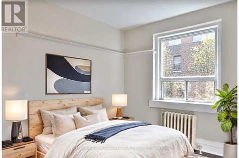 A bedroom with a large bed, a window, and a plant.