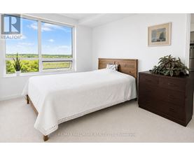 A bedroom with a large bed and a window overlooking a green landscape.