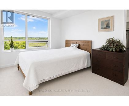 A bedroom with a large bed and a window overlooking a green landscape.