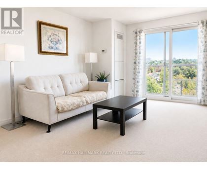 A living room with a white sofa, a black coffee table, and a painting on the wall.