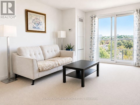 A living room with a white sofa, a black coffee table, and a painting on the wall.