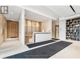 A spacious office lobby with a reception desk and a wall of shelves.