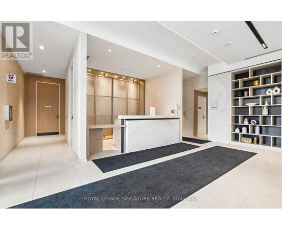 A spacious office lobby with a reception desk and a wall of shelves.