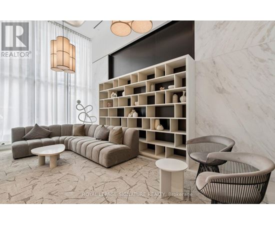 A modern living room with a grey sofa, a white coffee table, and a wall with a shelf.