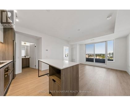 A spacious kitchen with wooden floors and white countertops.