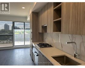 A modern kitchen with wooden cabinets and a marble backsplash.