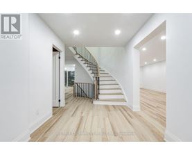 A white interior with a staircase and a brokerage logo.