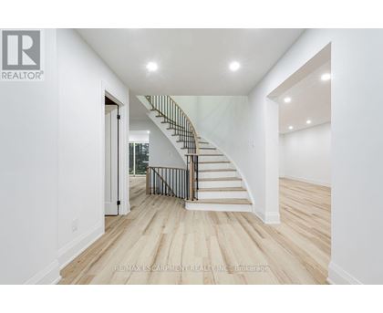 A white interior with a staircase and a brokerage logo.