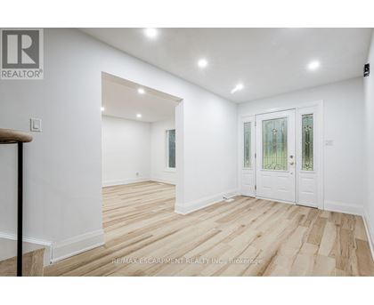 A room with white walls and wooden flooring, with a door on the right side.