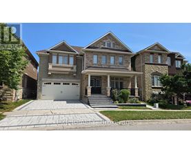 A large, two-story house with a garage is surrounded by a well-maintained lawn and a clear blue sky.