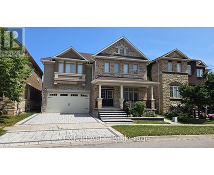A large, two-story house with a garage is surrounded by a well-maintained lawn and a clear blue sky.
