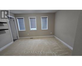 A room with a carpeted floor and two windows with blinds.