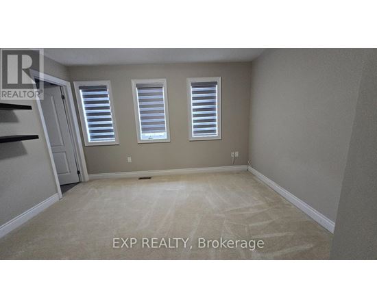 A room with a carpeted floor and two windows with blinds.