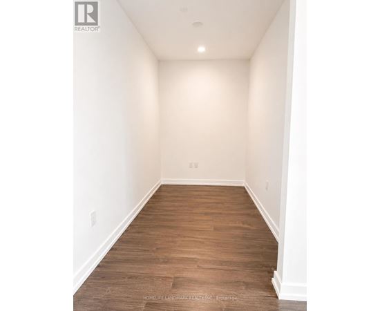 A long, empty hallway with wooden floors and white walls.