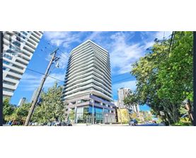 A tall building with a glass facade stands in the middle of a city street.