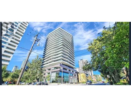 A tall building with a glass facade stands in the middle of a city street.