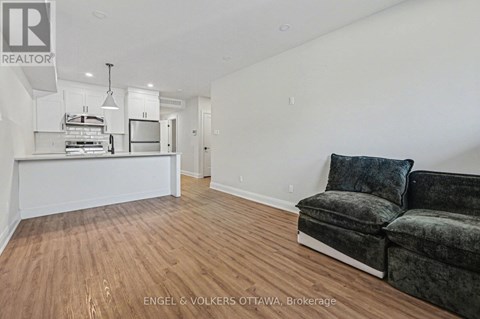 A living room with a grey couch and a kitchen area in the background.