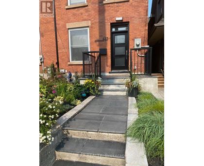 A brick house with a black front door and a small garden in front.