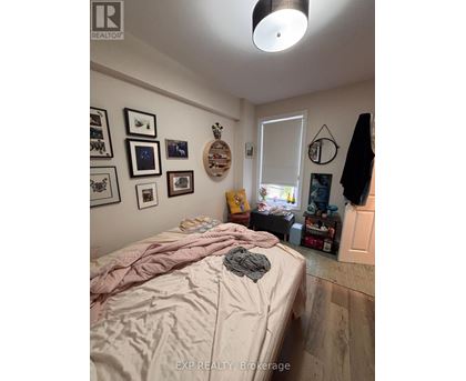 A bedroom with a bed covered in a pink comforter and a wooden wall hanging.