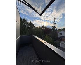 A balcony with a view of the sky and trees.