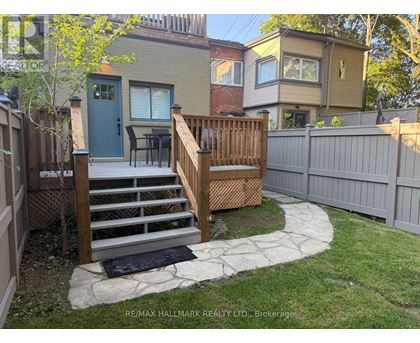 A backyard with a wooden deck and stairs leading to a house.