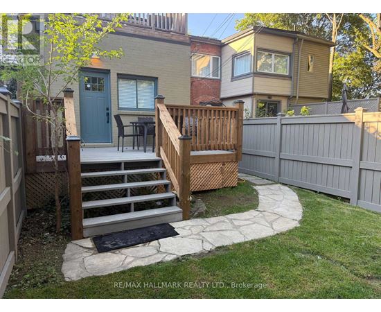 A backyard with a wooden deck and stairs leading to a house.