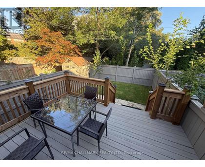 A glass table with four chairs is on a wooden deck.