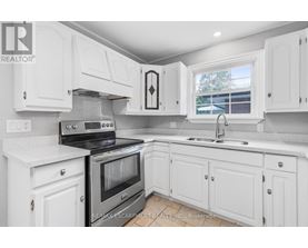 A white kitchen with a black stove top oven.