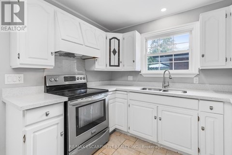 A white kitchen with a black stove top oven.