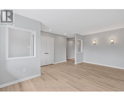 A spacious room with wood flooring and white walls.