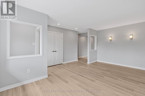 A spacious room with wood flooring and white walls.