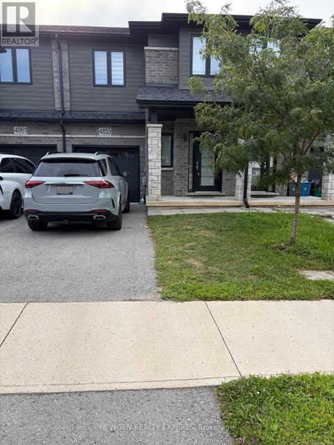 A grey SUV is parked in front of a house with a realtor sign.