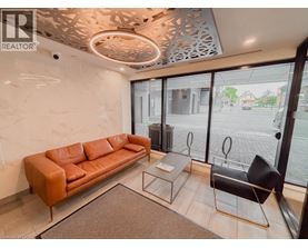 A living room with a brown leather couch, a glass table, and a black chair.