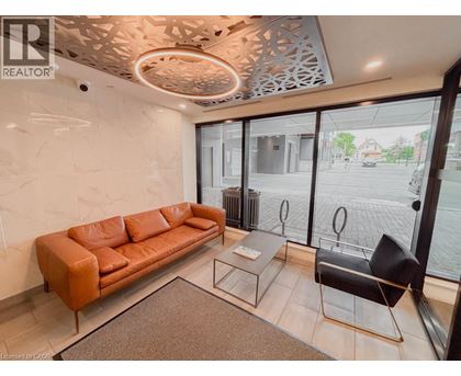 A living room with a brown leather couch, a glass table, and a black chair.