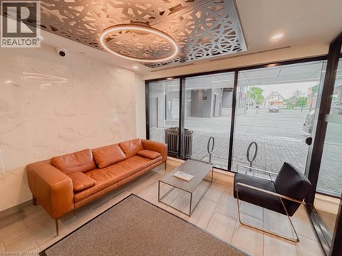 A living room with a brown leather couch, a glass table, and a black chair.