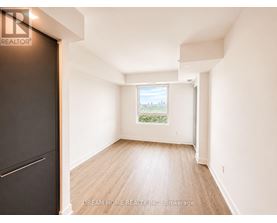 A room with a wooden floor and white walls, with a window showing a view of a cityscape.