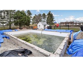 A construction site with a pool under construction surrounded by blue tarps.